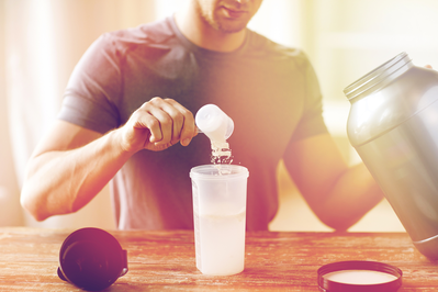 man putting protein powder into a smoothie