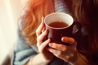female hands holding mug of warm tea