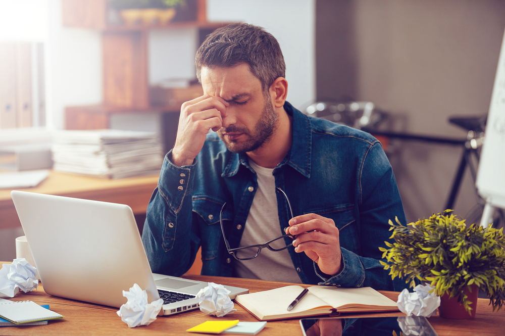 stressed man at work holding bridge of nose