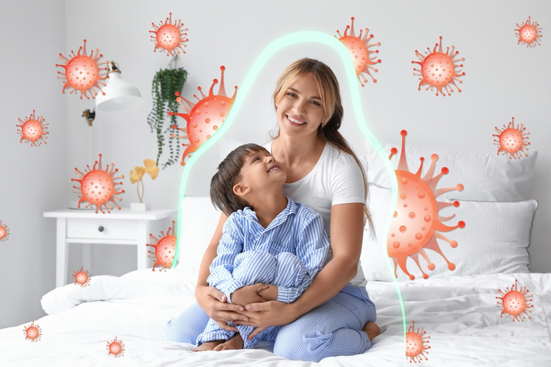 mother and son sitting on bed with barrier blocking out illustrated viruses